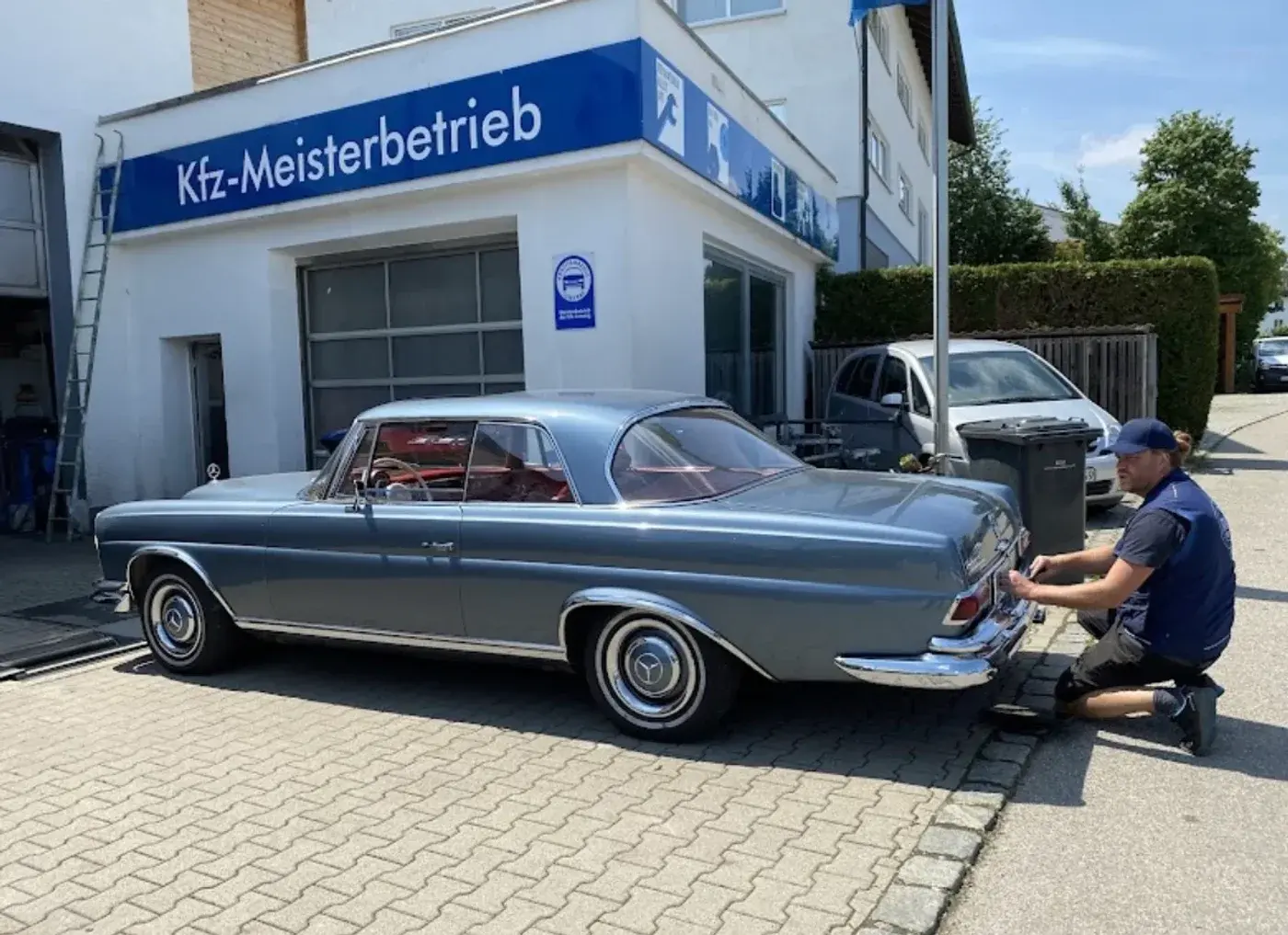 Mitarbeiter von Thot bei der Arbeit an einem klassischen Mercedes-Benz Coupé vor der Werkstatt